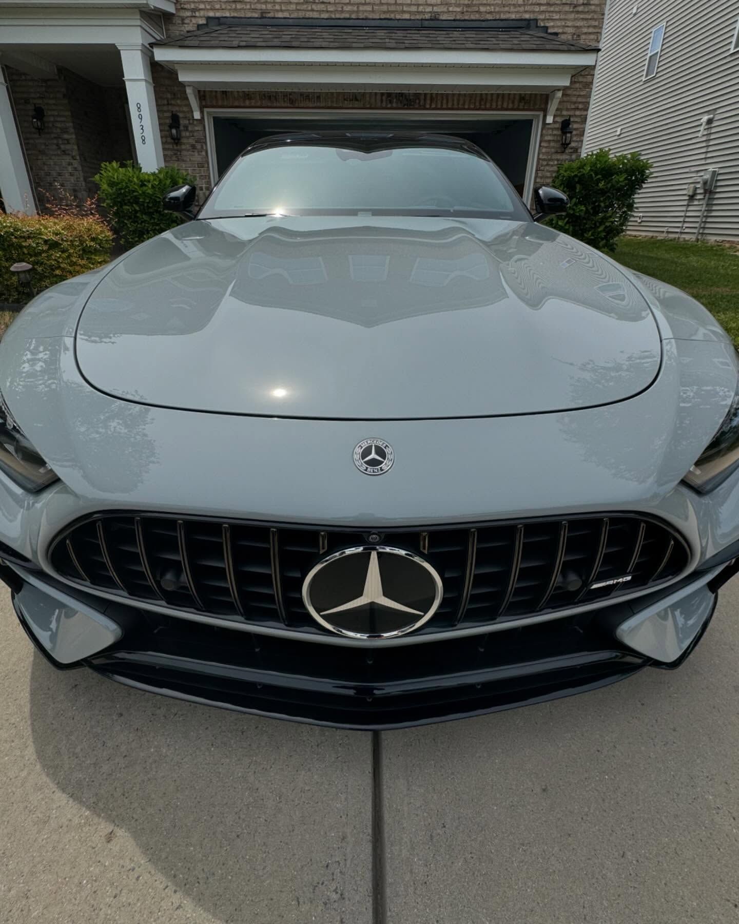 A mercedes benz sports car is parked in front of a house.