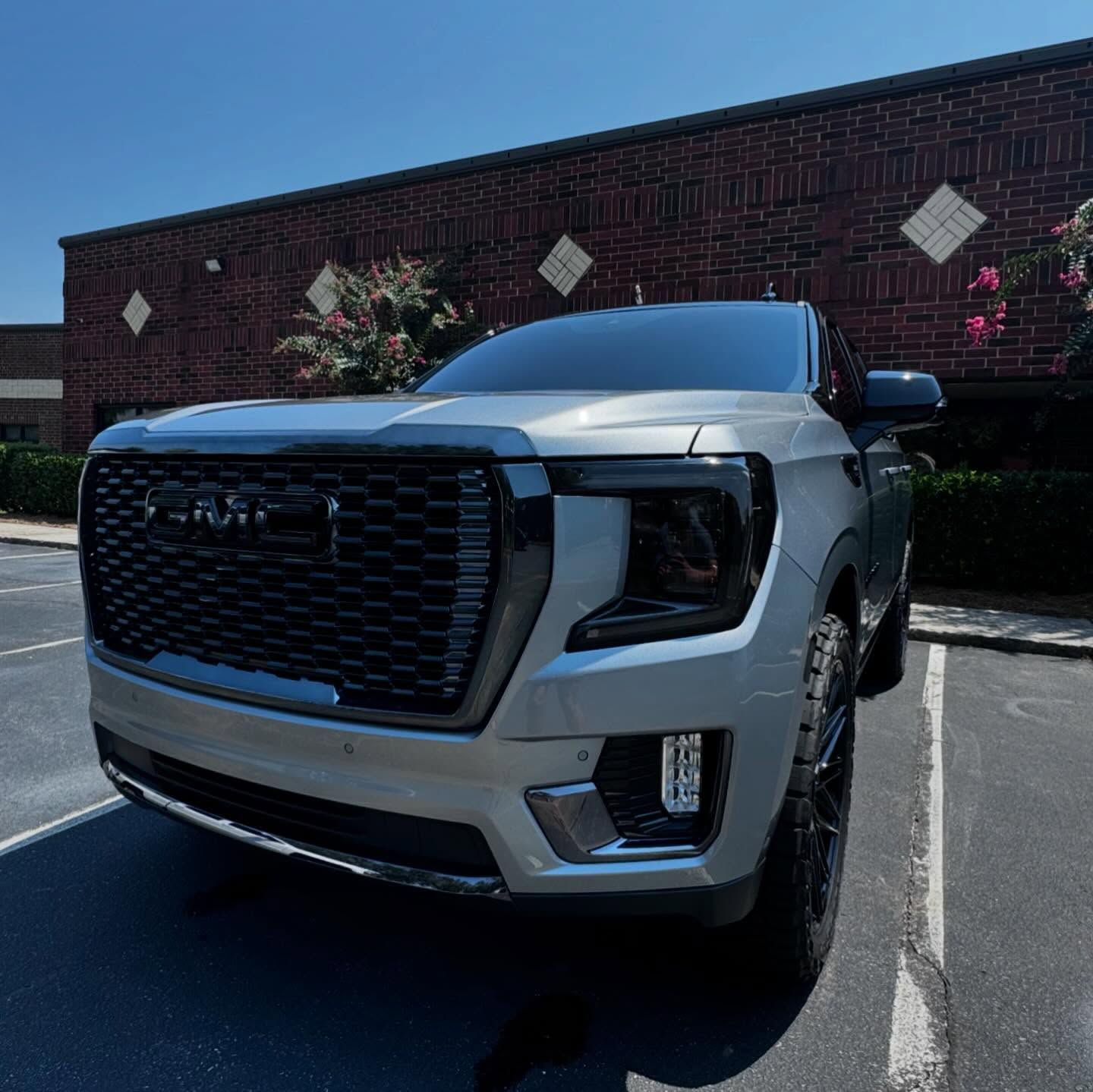 A silver truck is parked in front of a brick building.