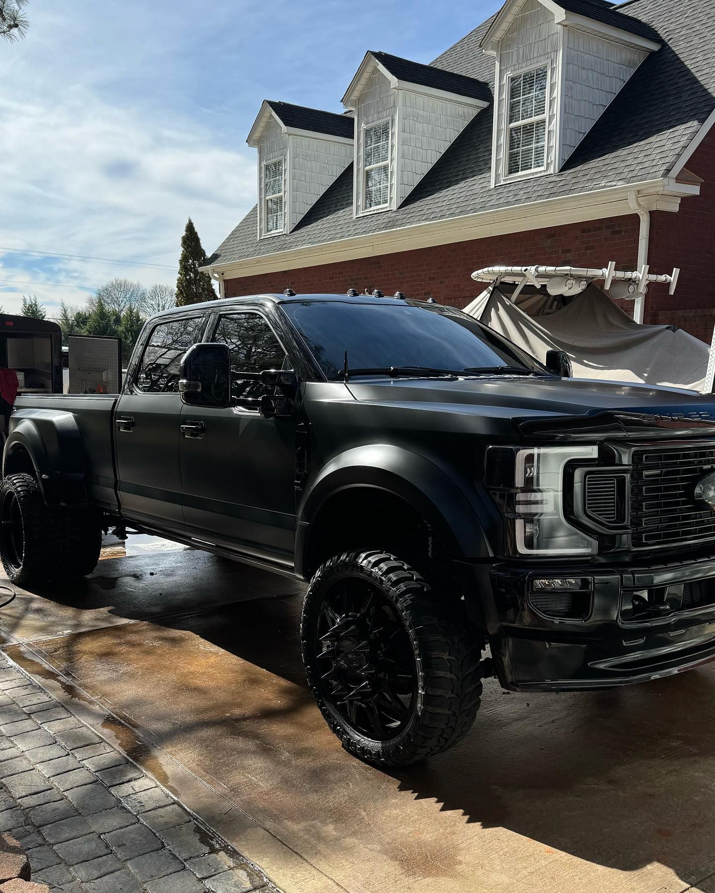 A black truck is parked in front of a brick house.