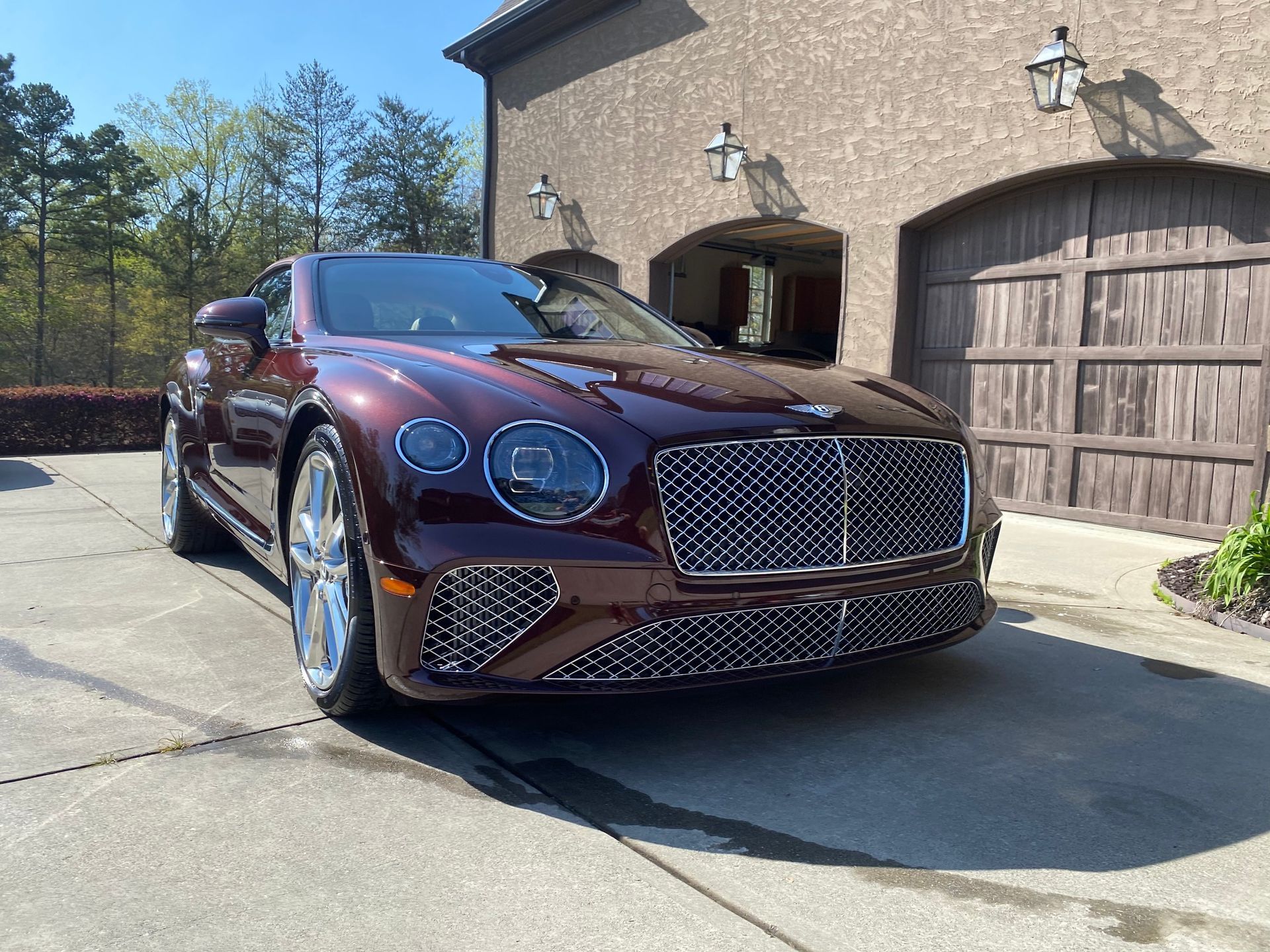 A red bentley is parked in front of a garage.