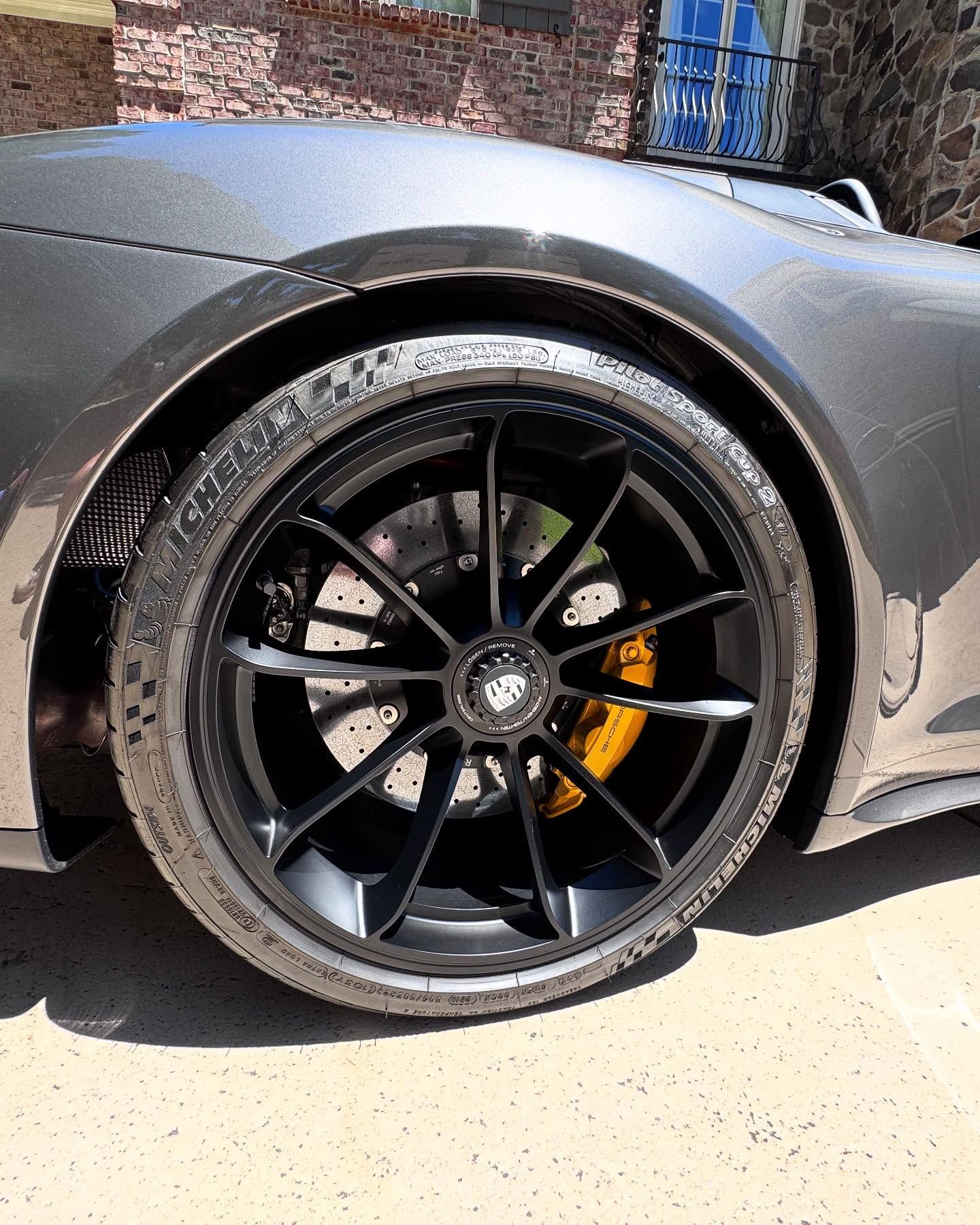 A close up of a car wheel with a yellow brake caliper