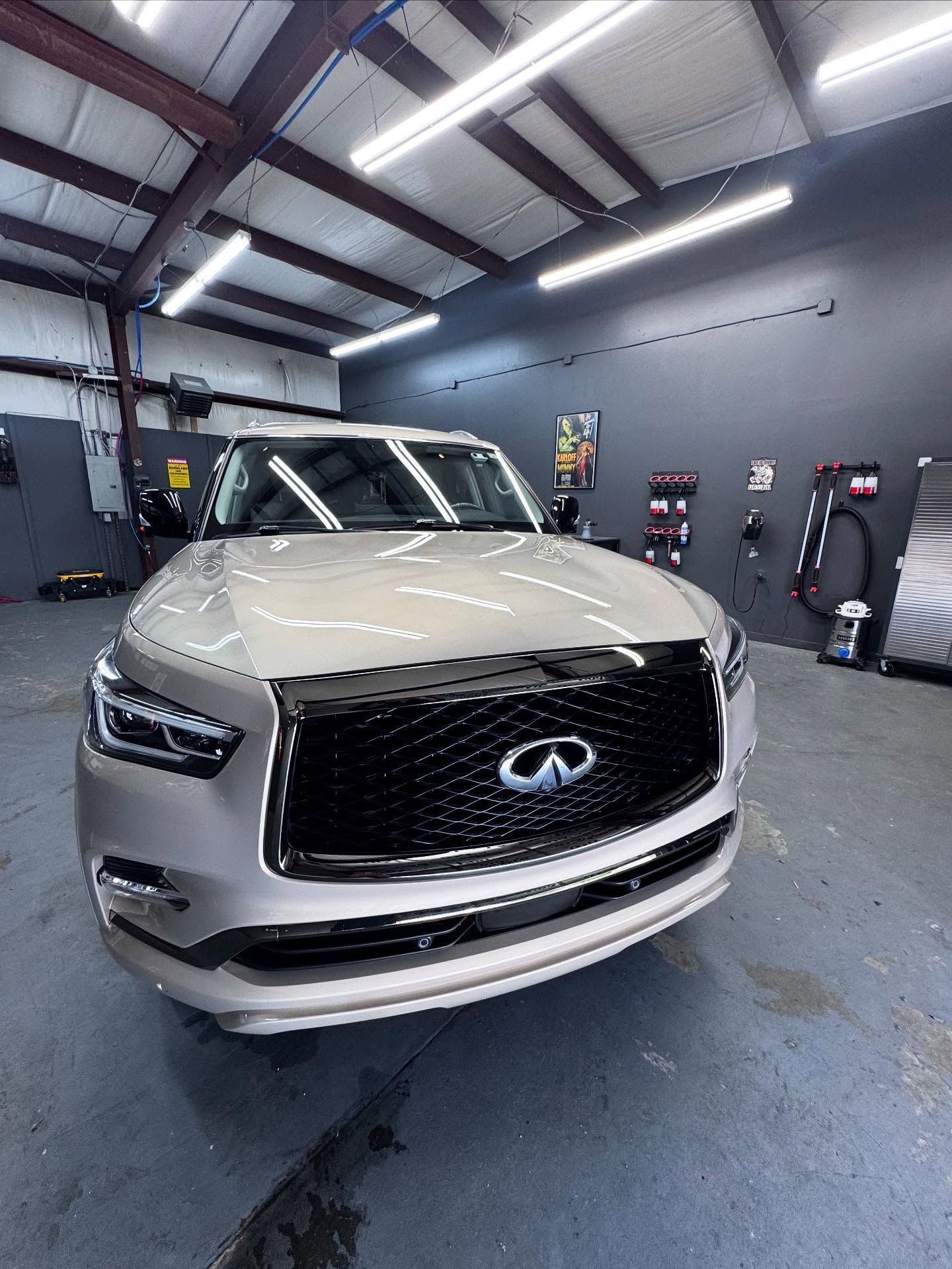 A silver infiniti is parked in a garage.