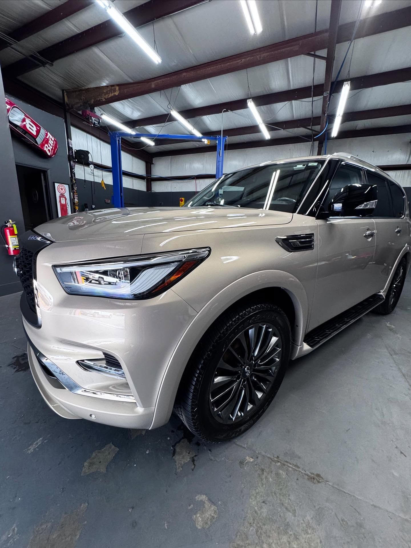 A silver infiniti qx80 is parked in a garage.