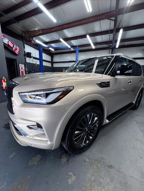 A silver infiniti qx80 is parked in a garage.