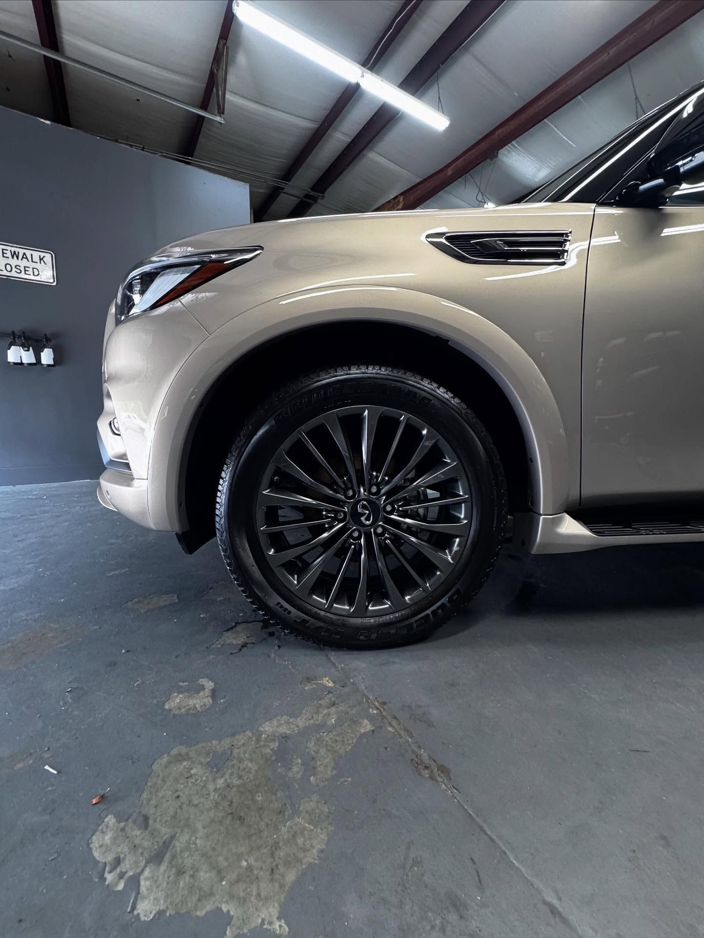 A silver car is parked in a garage with a black tire.