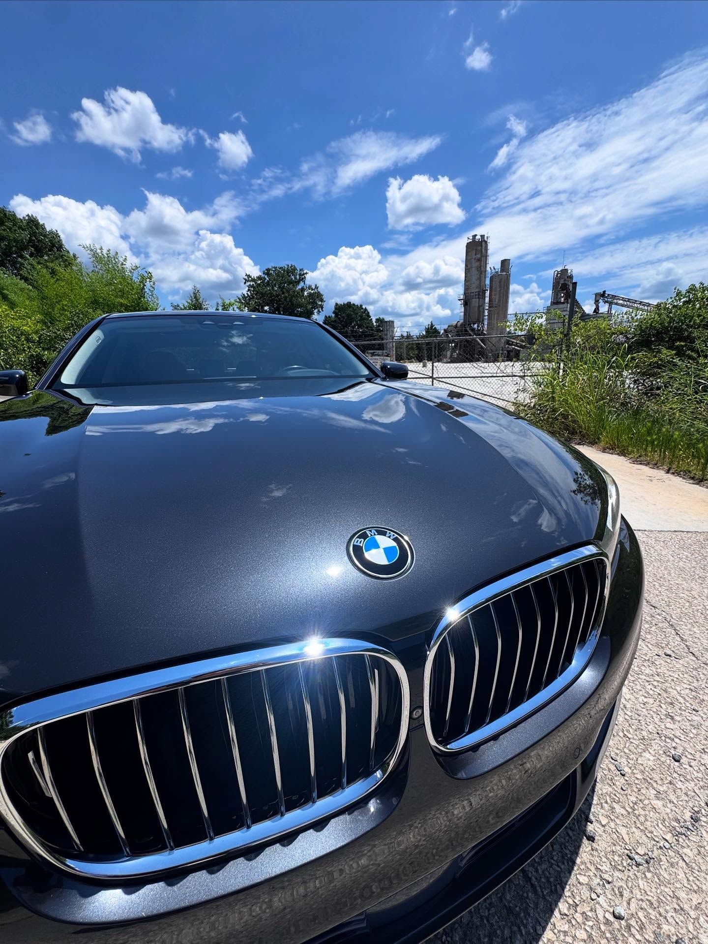A black bmw is parked on the side of the road.