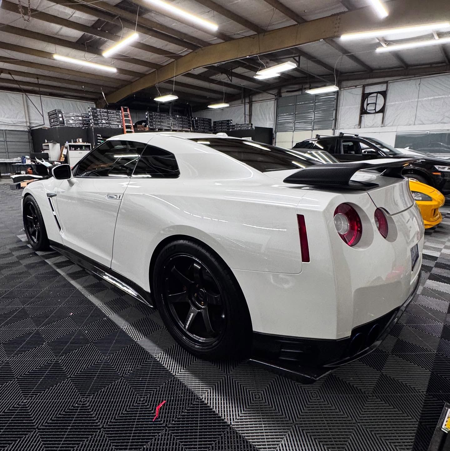 A white sports car is parked in a garage.