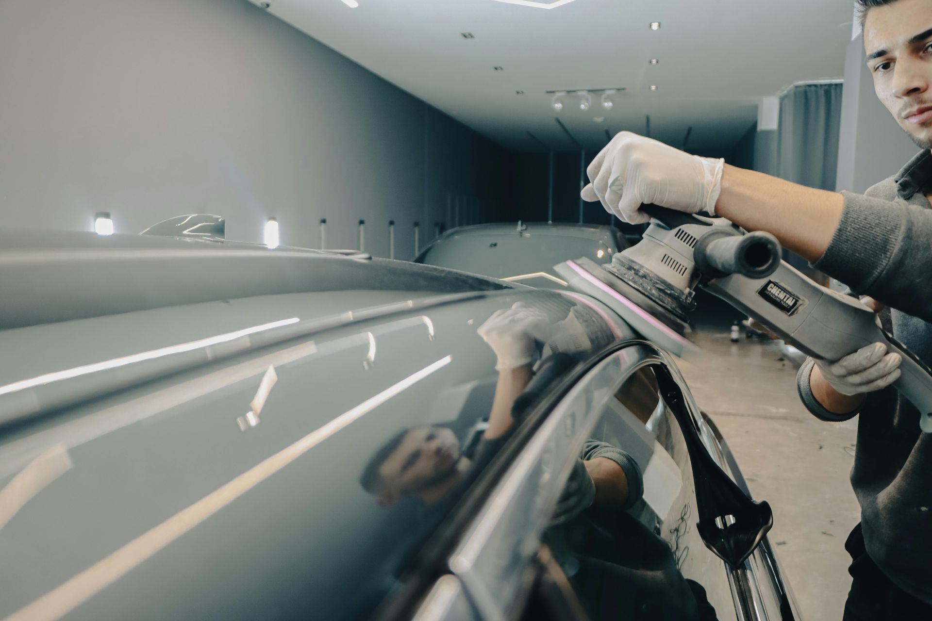A man is polishing a car with a machine.
