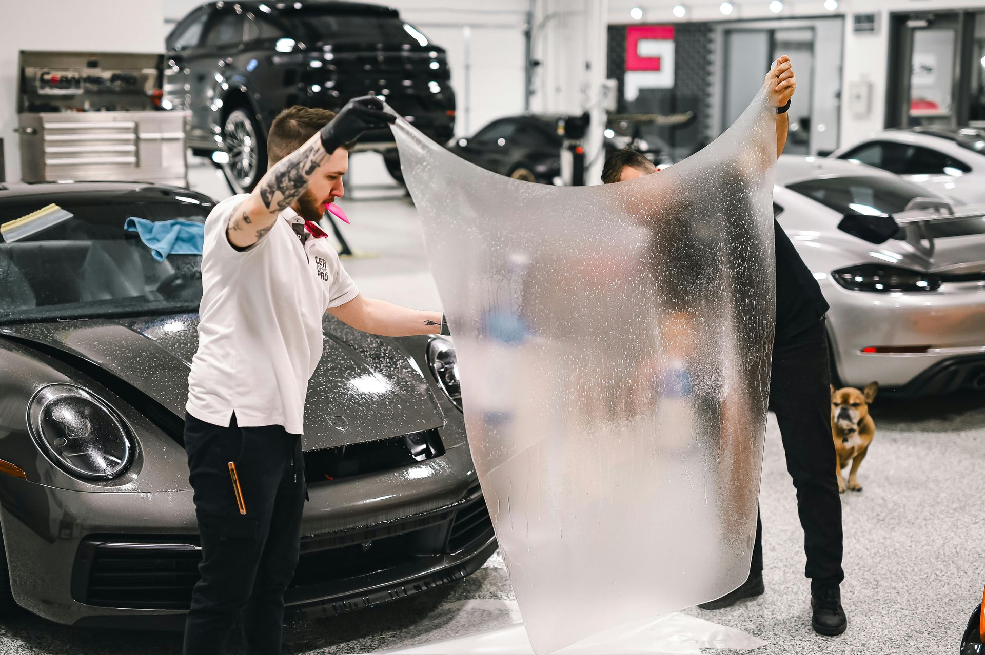 A man is wrapping a car with a piece of plastic.