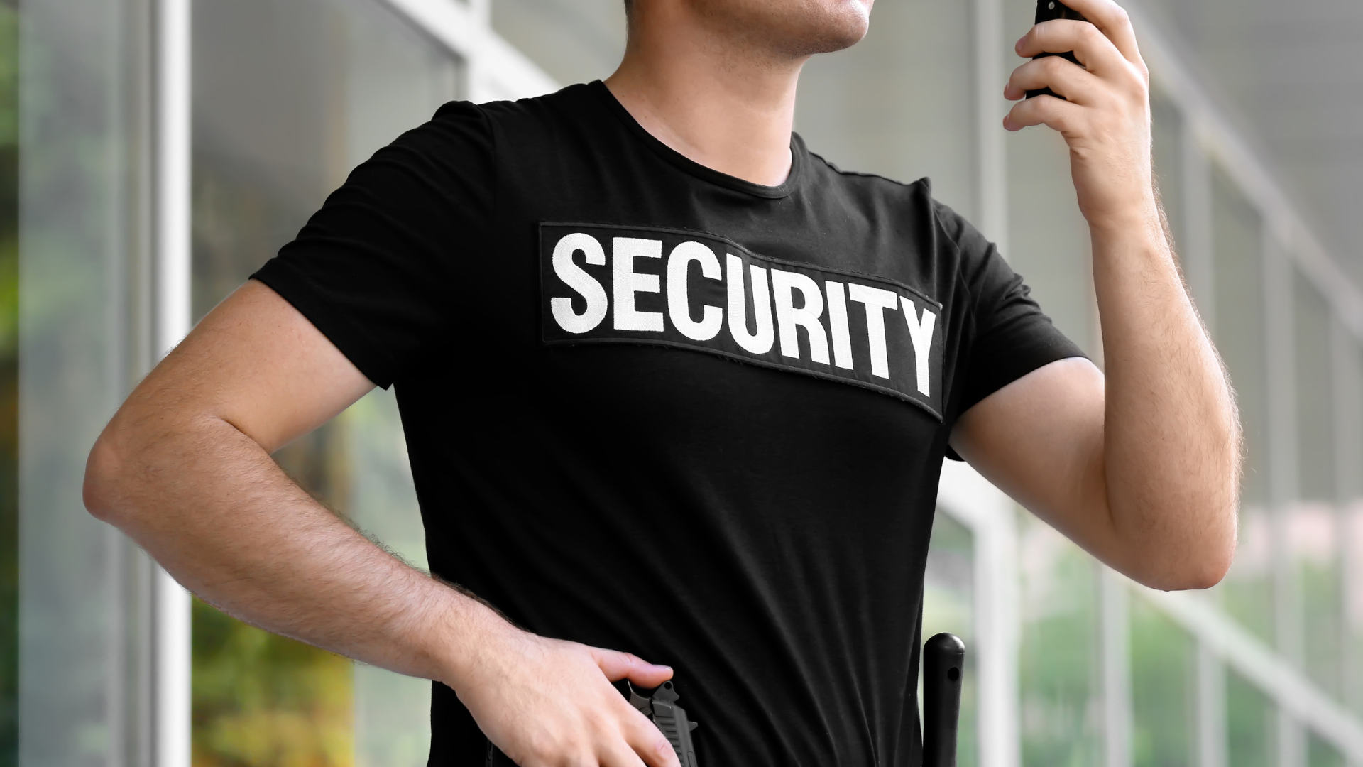 A security guard is talking on a walkie talkie.