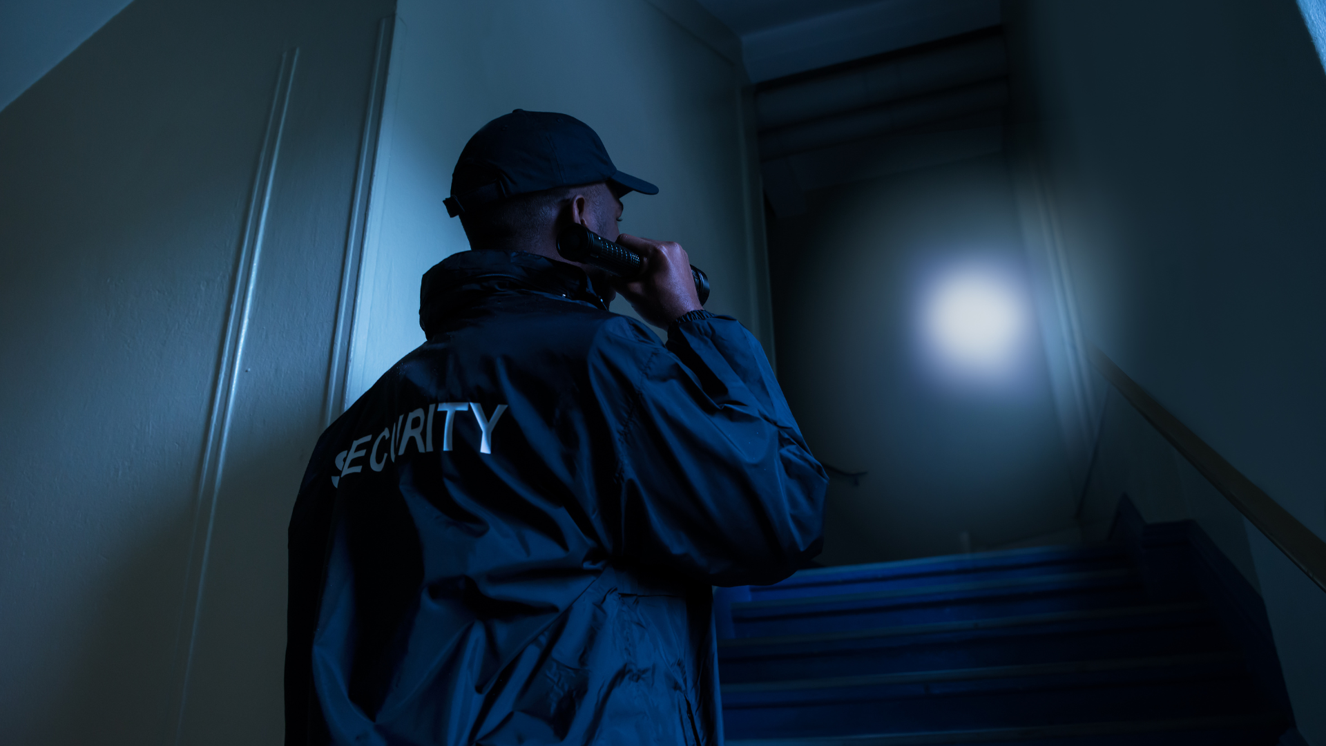 A security guard is talking on a walkie talkie in a dark room.