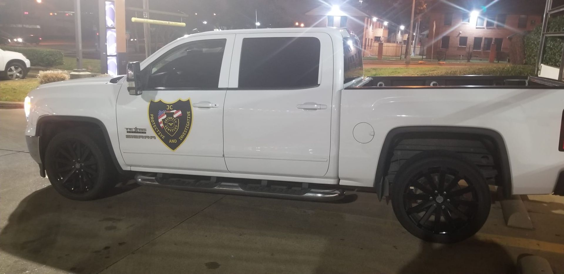 A white truck is parked in a parking lot at night.