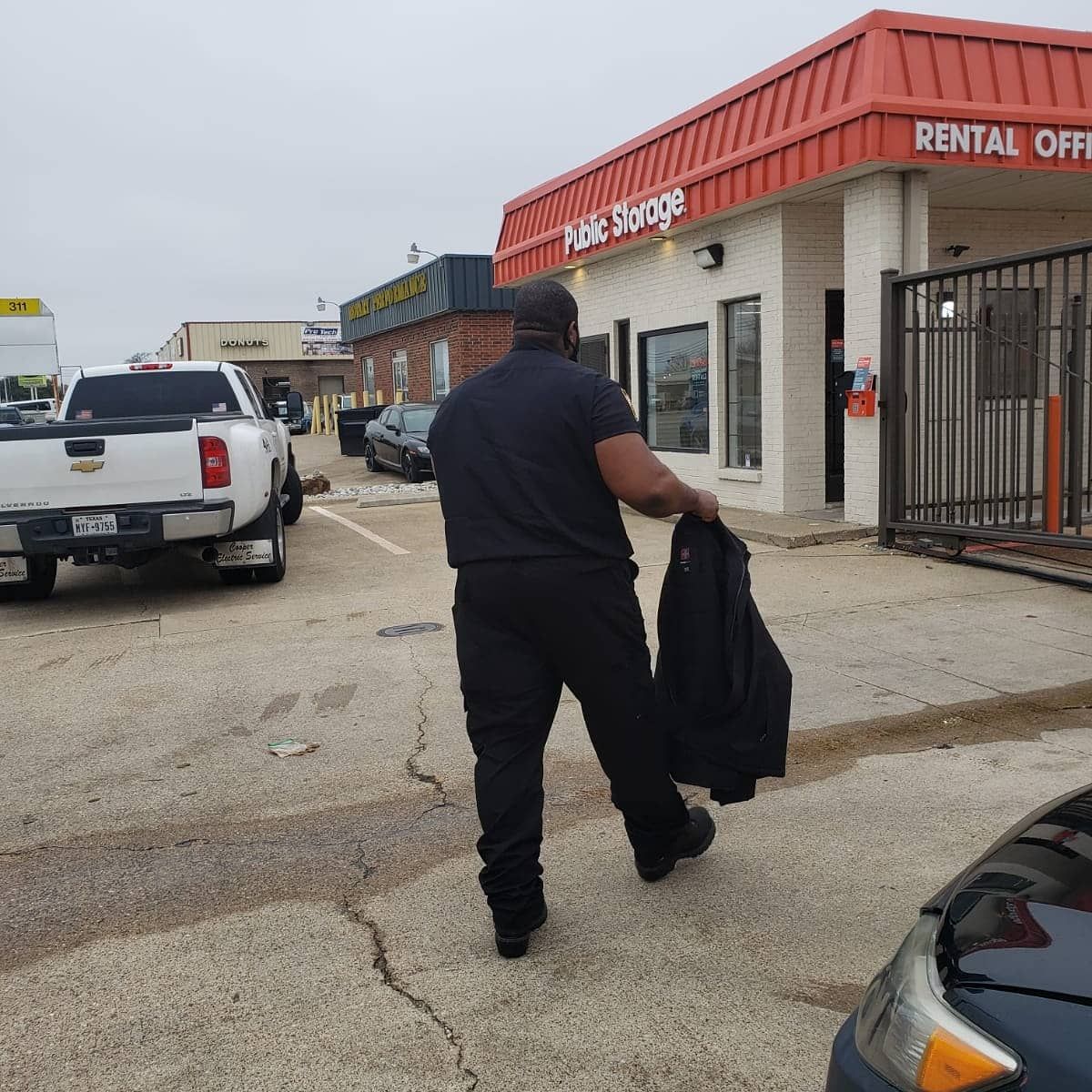 A man walking in front of a building that says public storage