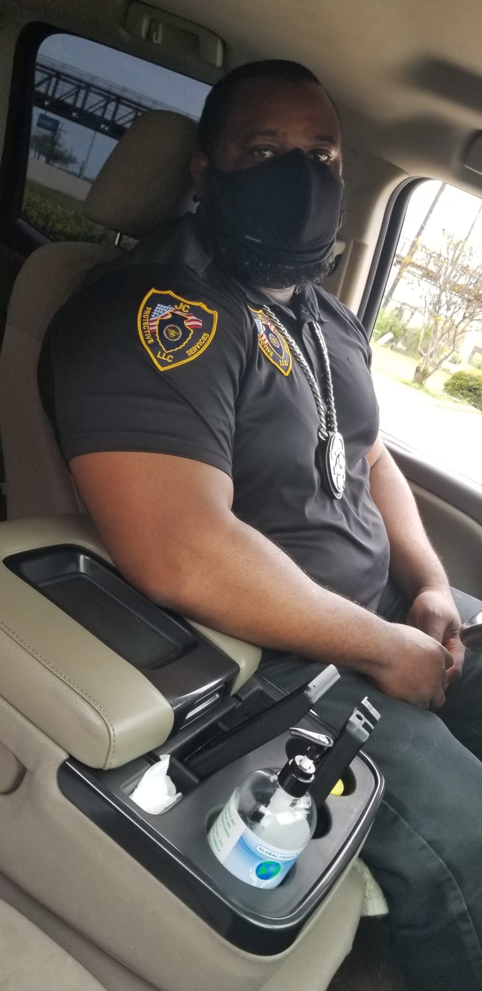 A man wearing a mask is sitting in the back seat of a car.