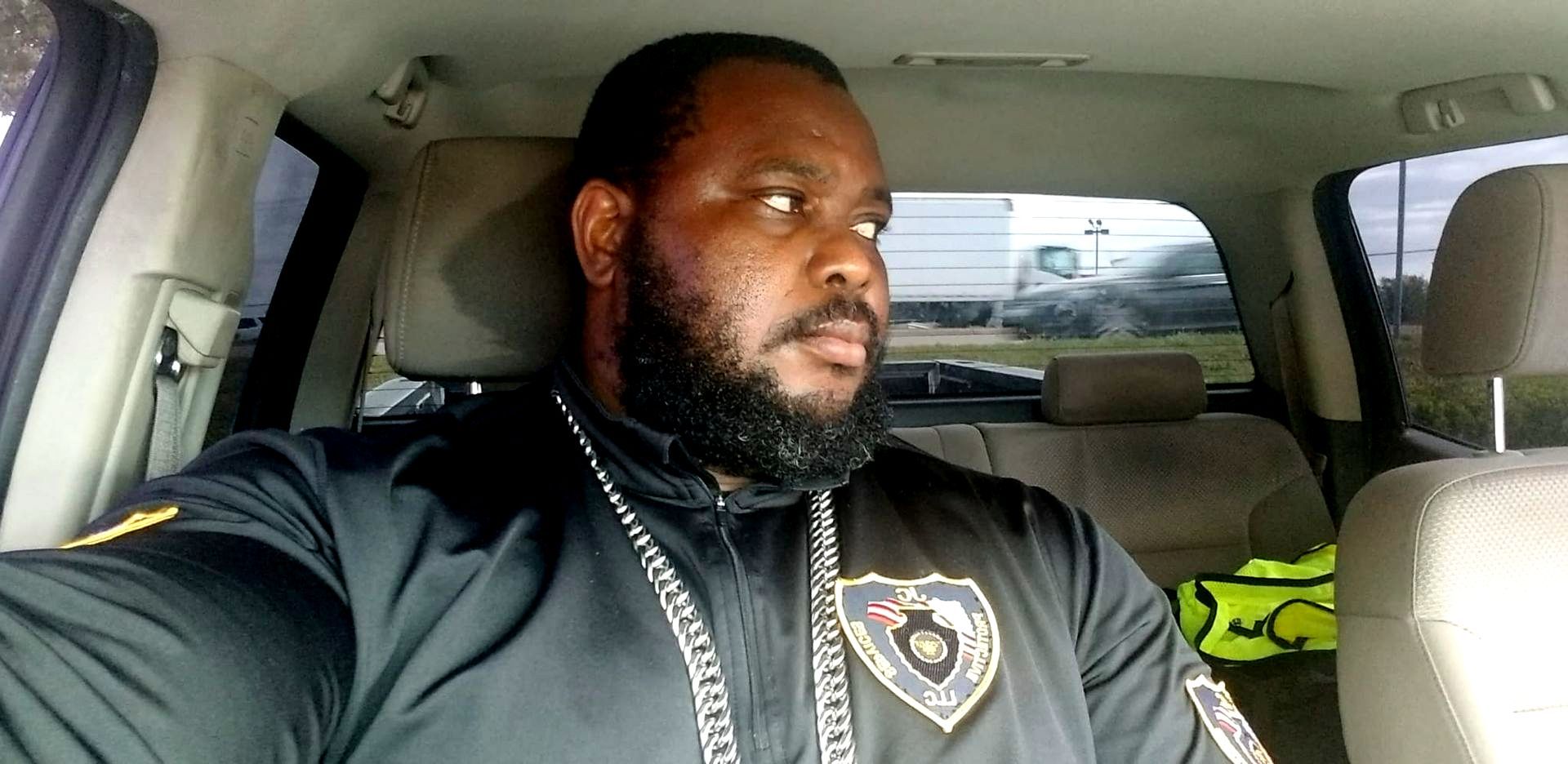 A man with a beard is sitting in the back seat of a car.