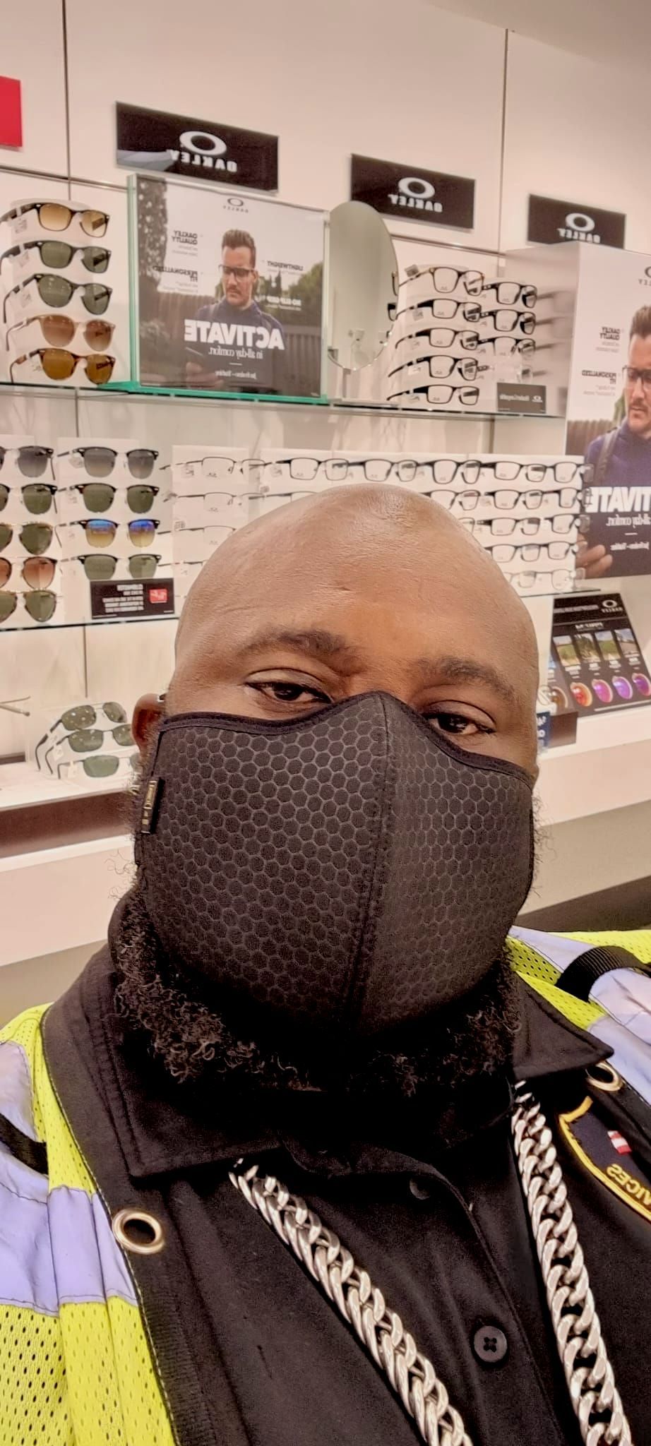 A man wearing a mask is standing in front of a store.