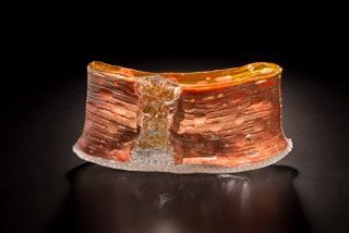 Sectioned micro-coil device, copper coils encased in clear resin, set against a dark background.