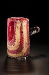 Red and tan swirled glass mug with a clear handle, set against a black background.