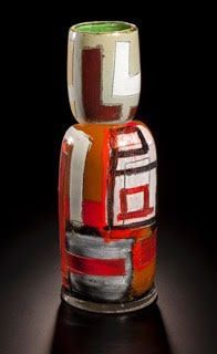 Abstract glass vase with red, white, and brown geometric shapes against a dark backdrop.