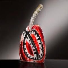 Red and white abstract glass sculpture with a clear, curved handle against a black background.