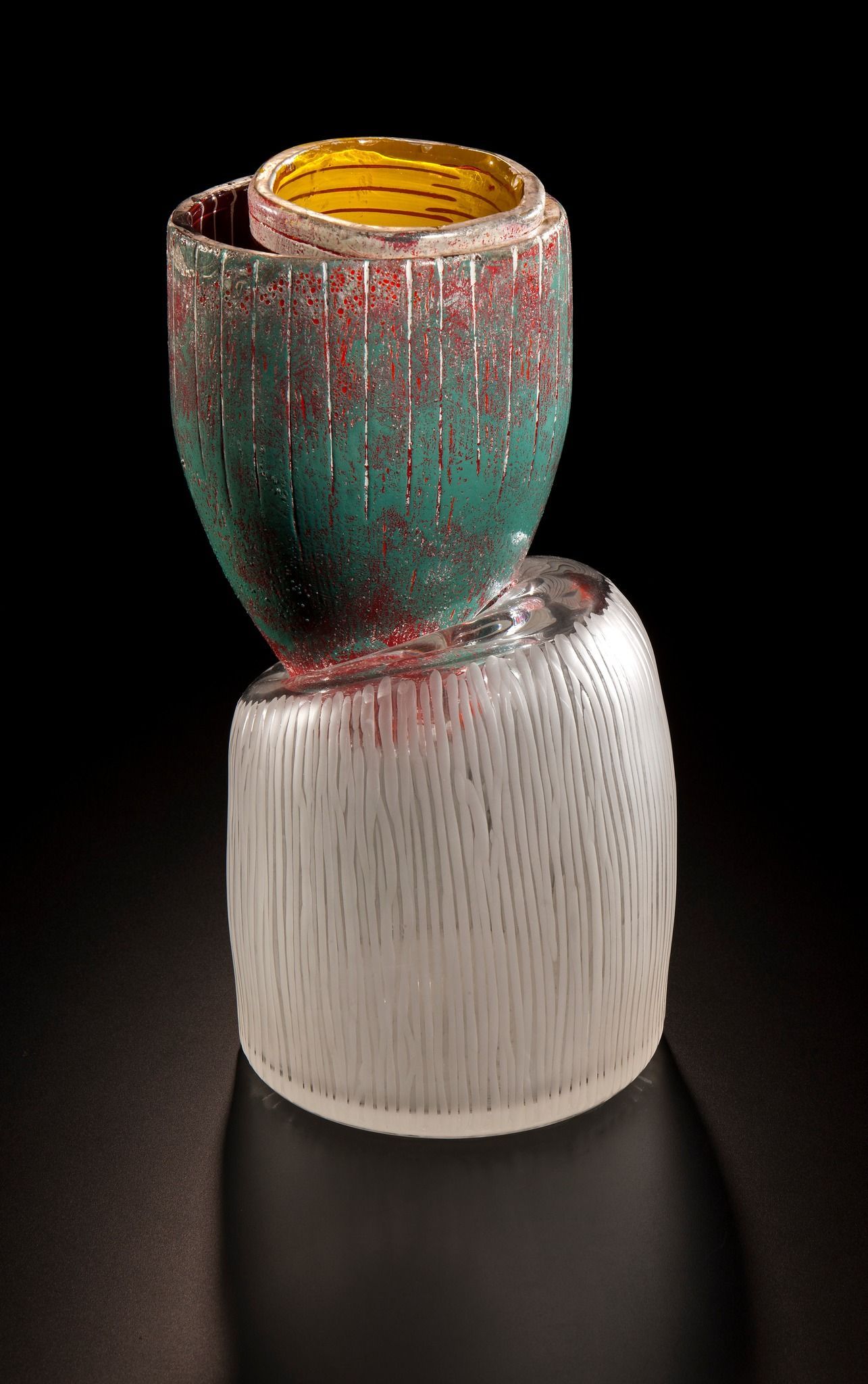 Sculptural glass vase with green, red, and clear sections, and a yellow interior.