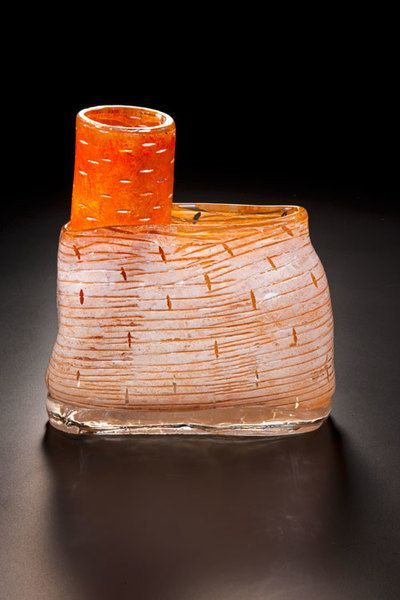 Glass sculpture. Orange cylindrical shape atop a brick-like textured base.