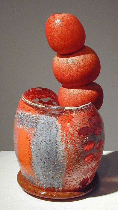 Red ceramic sculpture with stacked spheres atop a textured vase, orange and gray glaze.