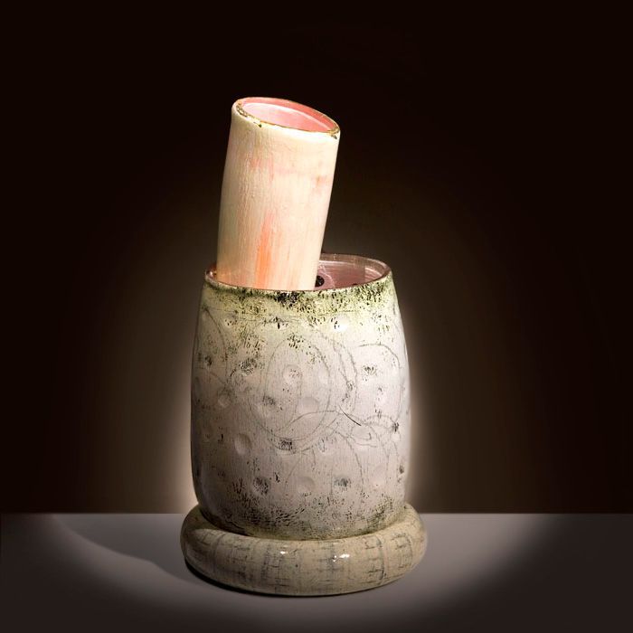 Ceramic sculpture: tall, cylindrical base with a smaller cylinder inside at an angle; off-white, pink, and green.