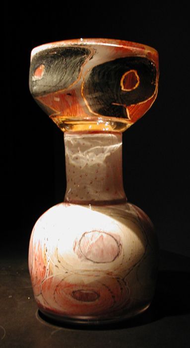 Glass vase with dark swirls, red accents, and a bulbous base, set against a black background.