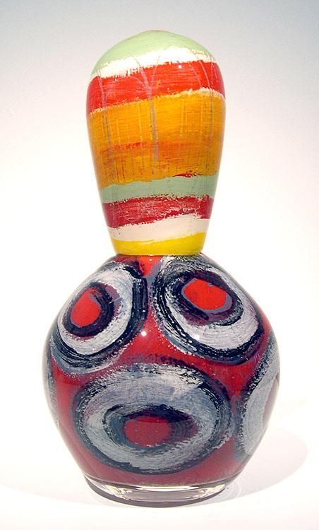Glass sculpture: bulbous red base with gray and white rings, supporting a colorful striped top.