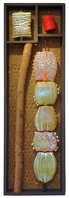 Abstract art piece with wooden frame, layered textures, and stacked, beaded orbs in various colors.