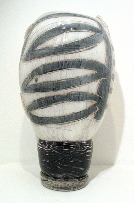 Ceramic sculpture of an egg shape with a spiral design and a black base.