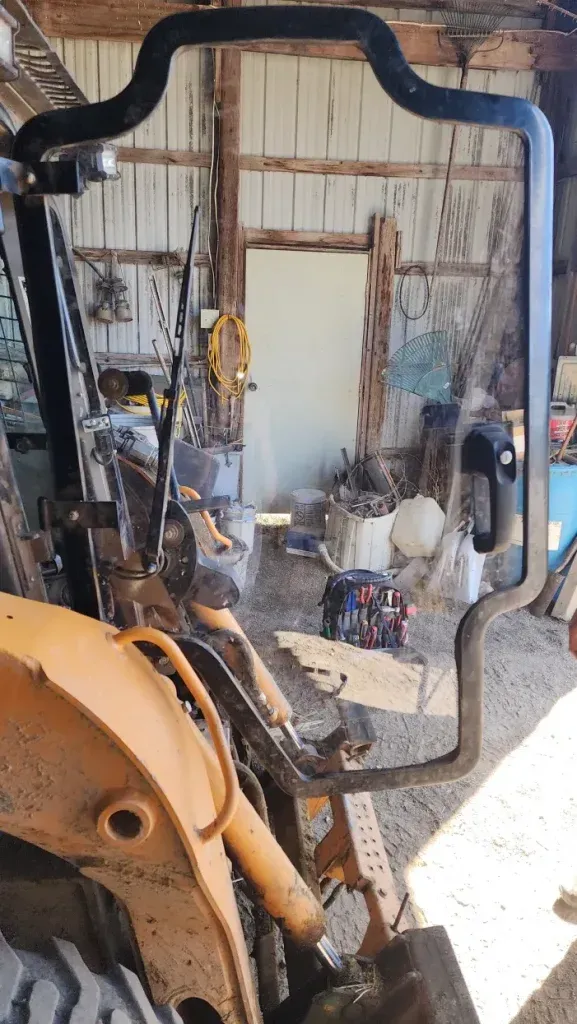 Black roll-over protection system on a yellow tractor; a shed interior is visible in the background.