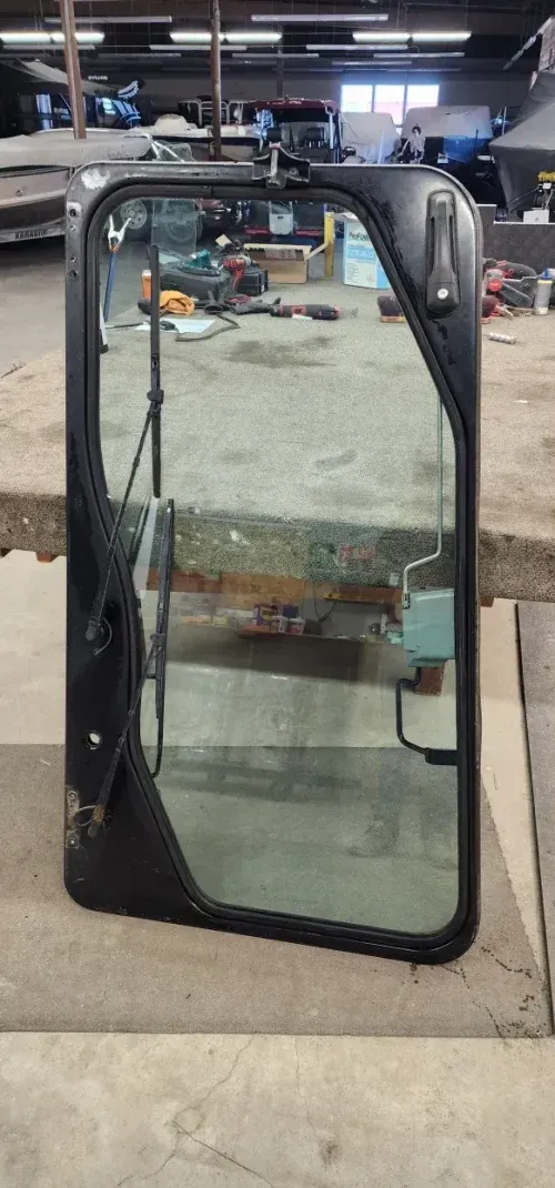 Black cab door with glass panel, on a concrete surface.