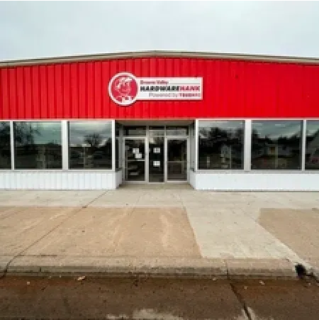 Red building: Bowman Valley Hardware Hank store, glass windows, and gray sidewalk.