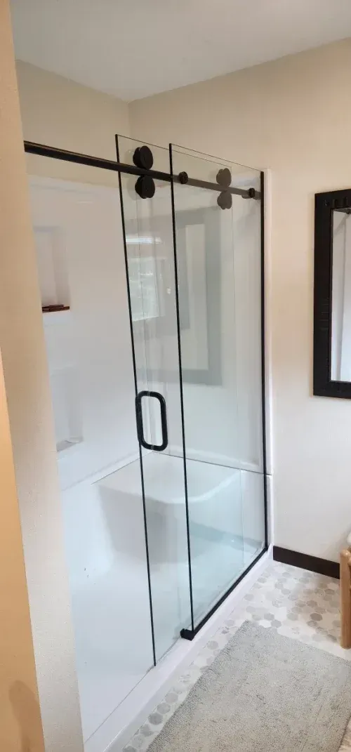 A modern bathroom with a sliding glass shower door with black hardware.