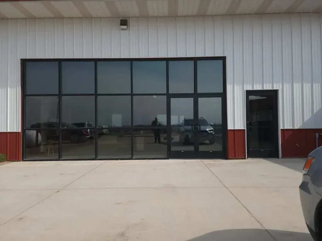 Building exterior with large tinted windows, a side door, and a concrete surface.