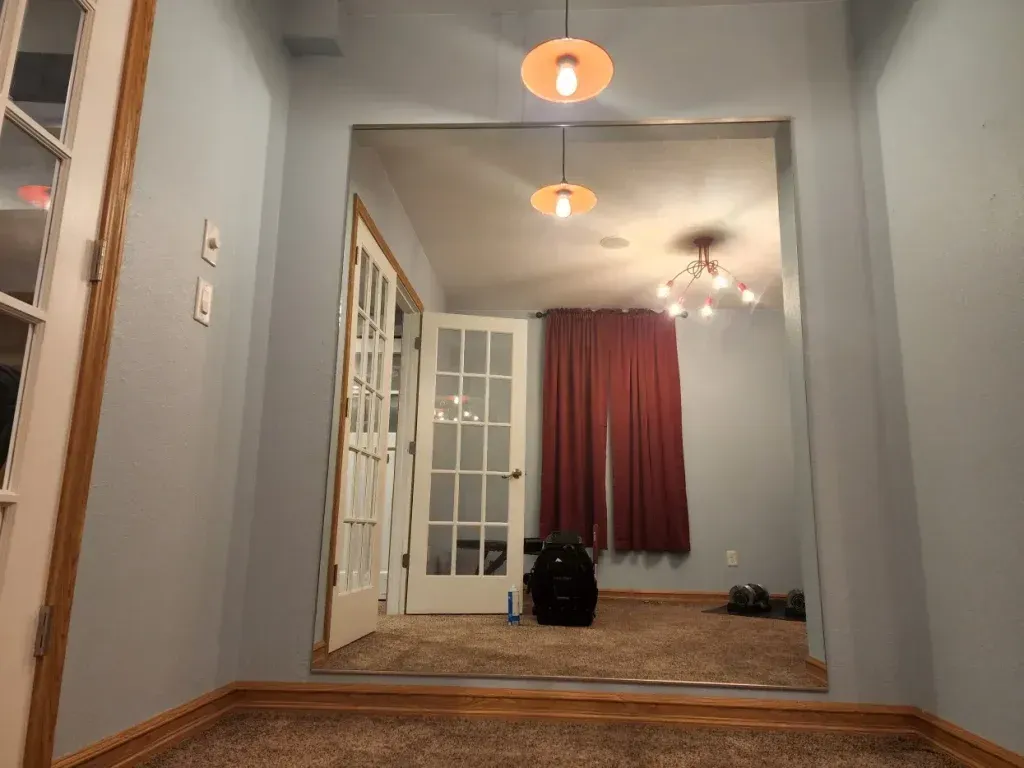 View through an archway into a room with French doors, a red curtain, and two pendant lights.
