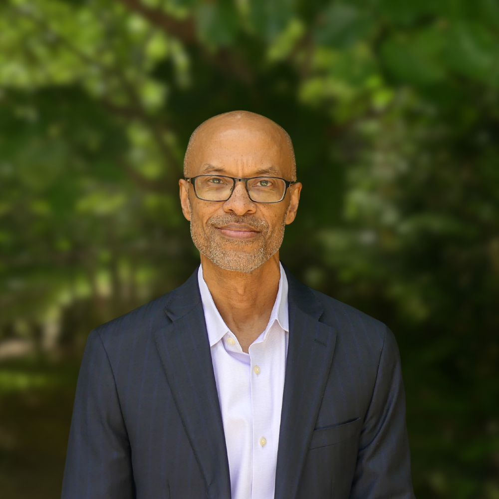 A picture of Gerard Etienne, MCAEL's new Executive Director. He wears a navy-blue suit.