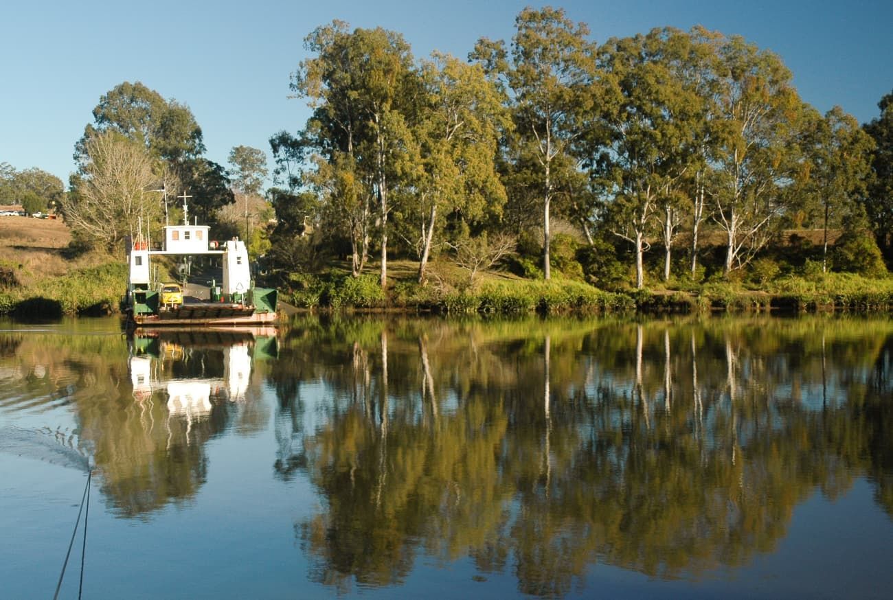 A Boat is Floating on a Lake With Trees in the Background — Breathe Easy Solutions In Kenmore, QLD