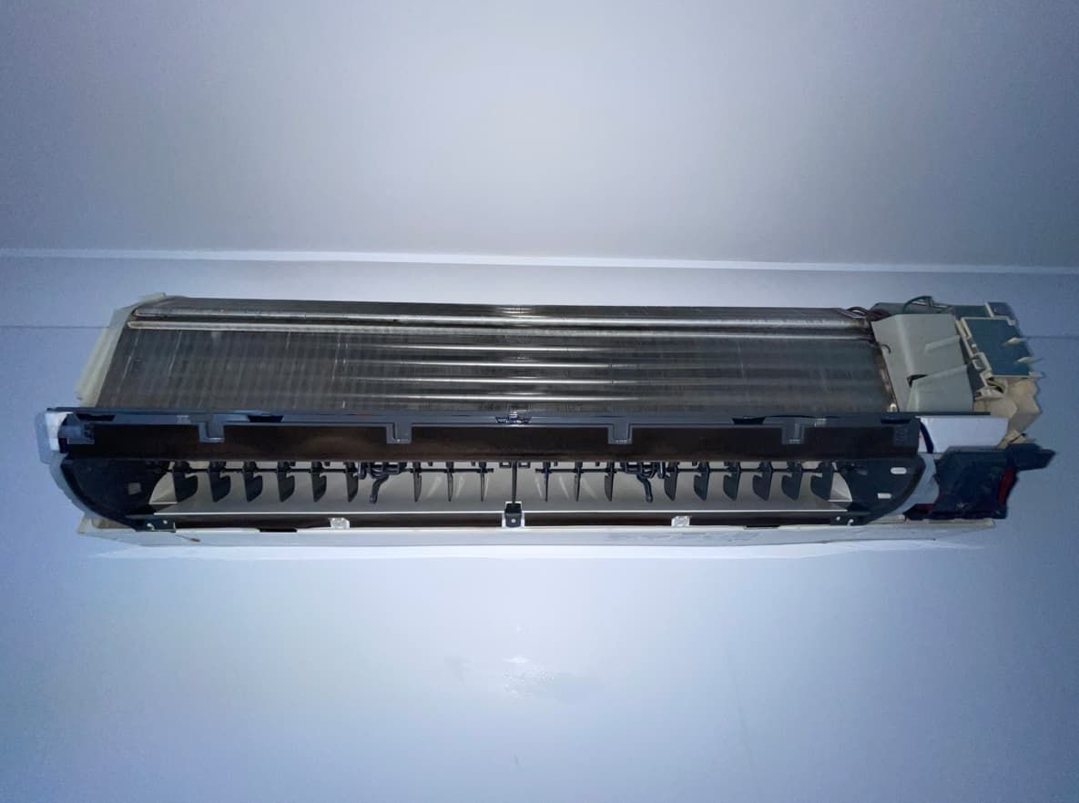 The inside of an air conditioner is sitting on a white surface.