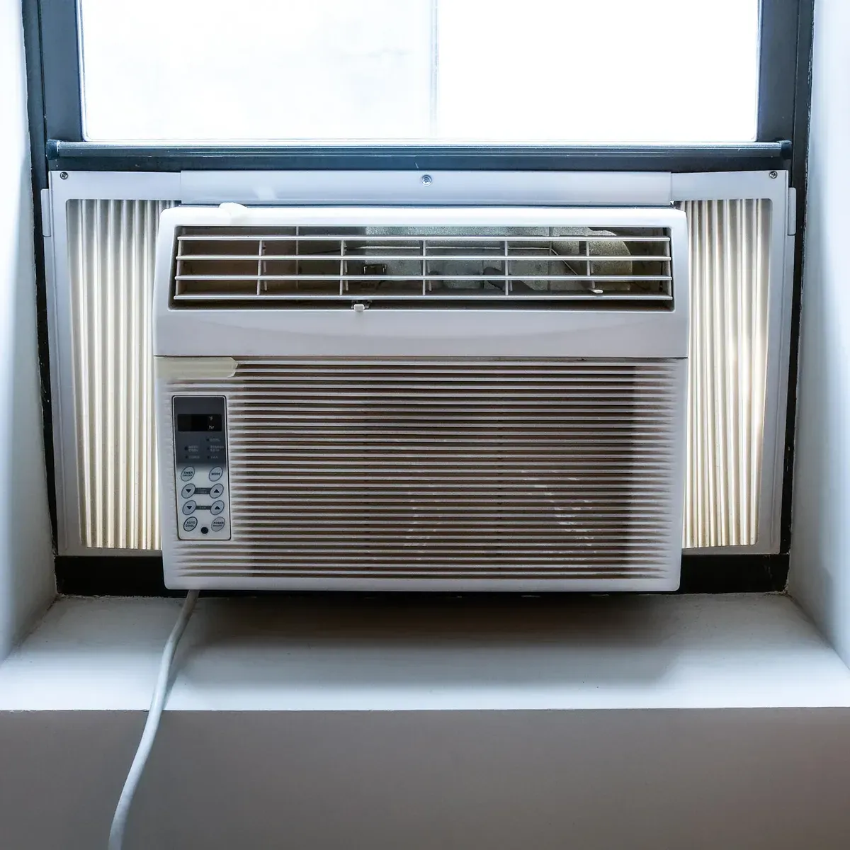 A white air conditioner is hanging on a yellow wall