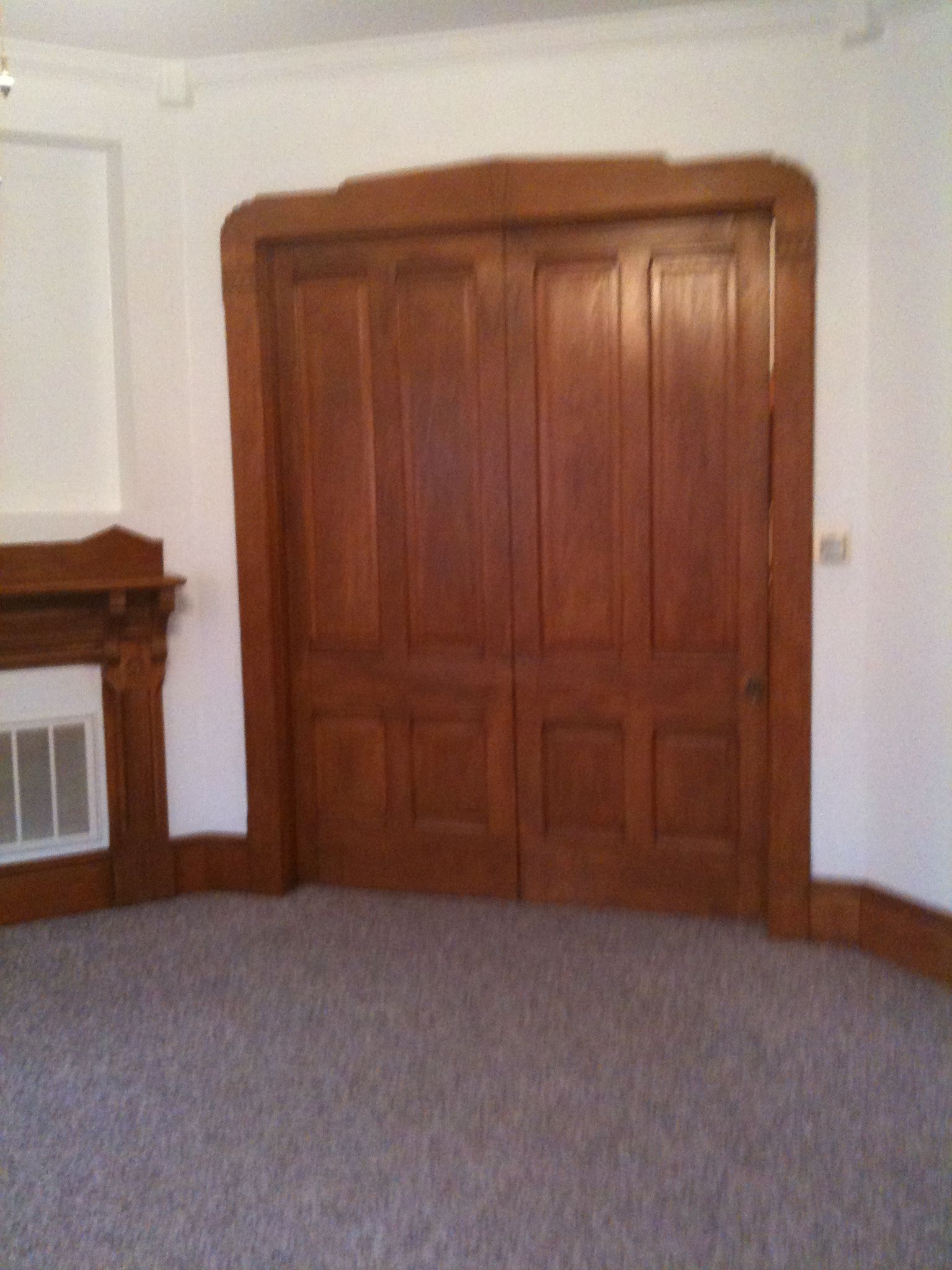 An empty room with a fireplace and wooden doors