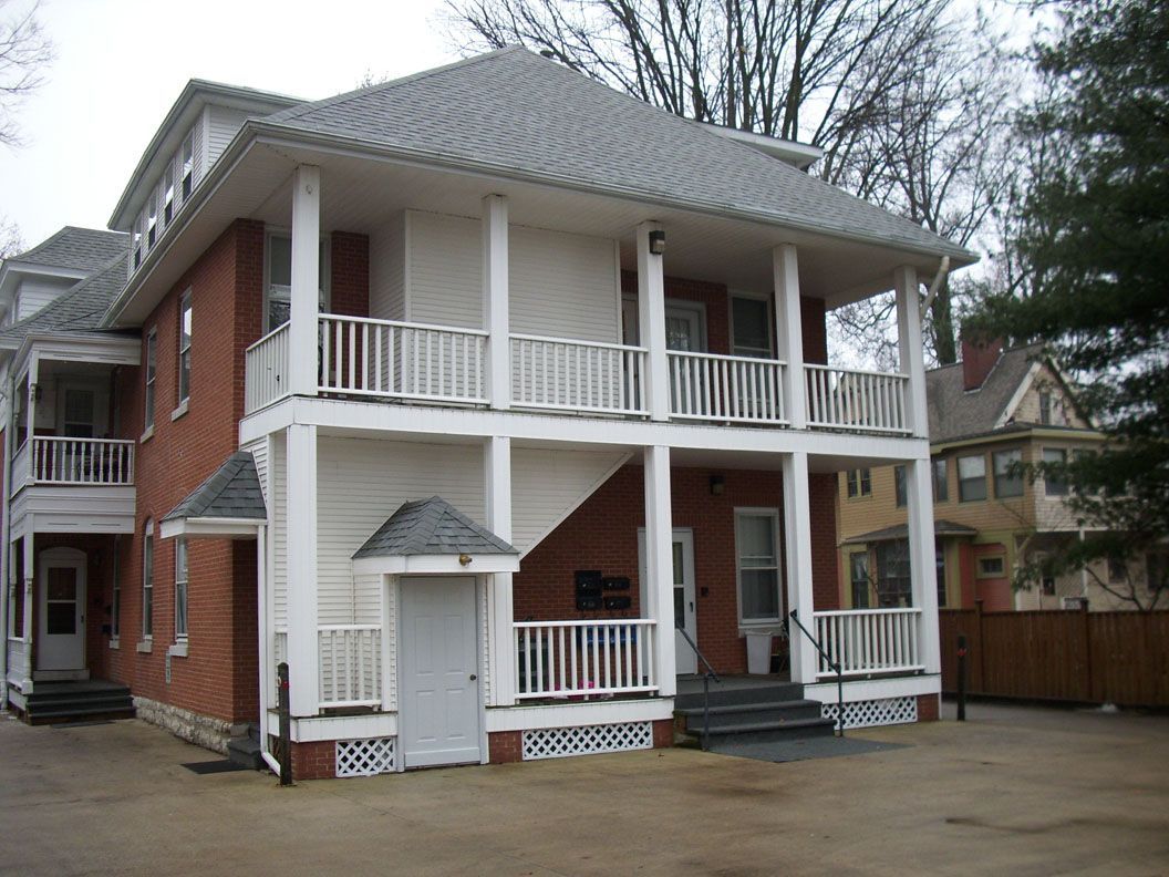 A large brick house with a white porch and stairs