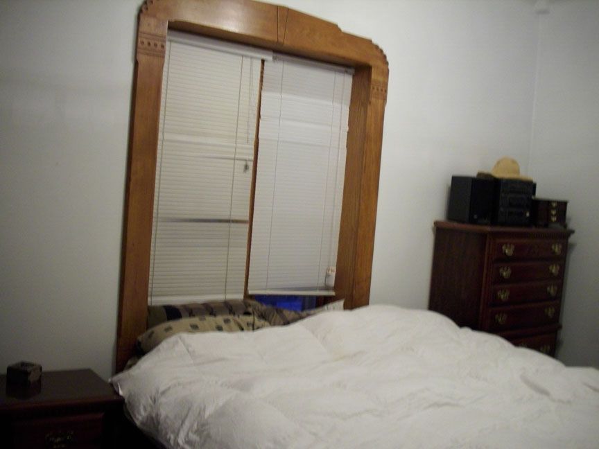 A bedroom with a bed and a window with blinds