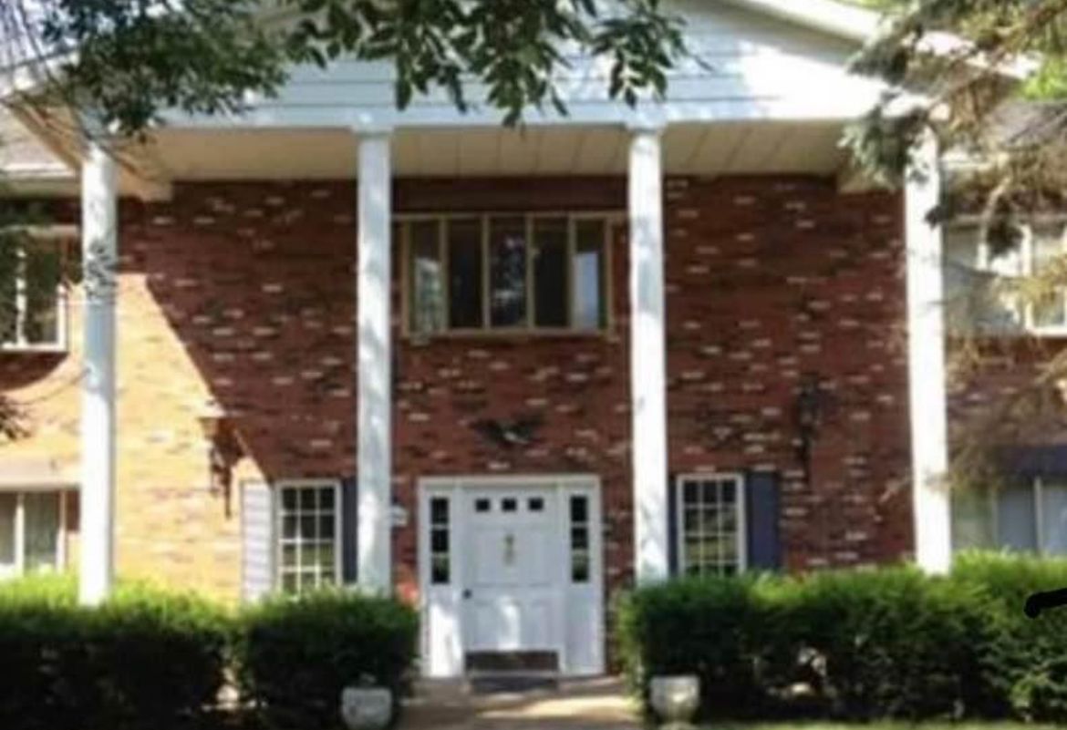 A large brick house with white columns and a white door