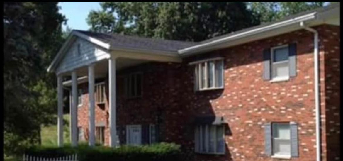A brick apartment building with a porch and shutters