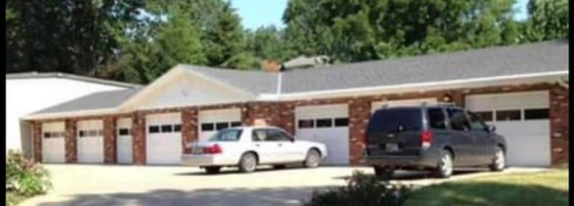 Two cars are parked in front of a house with garages