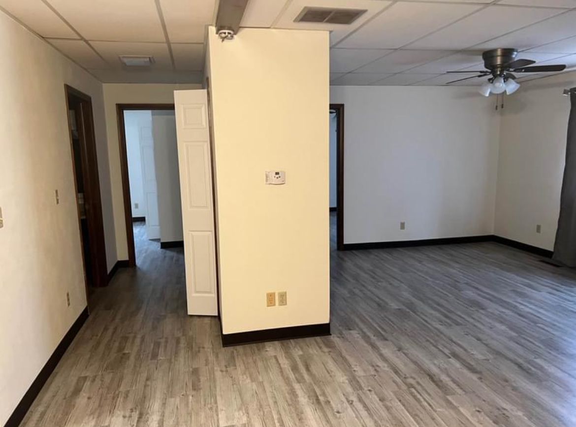 An empty room with hardwood floors and a ceiling fan