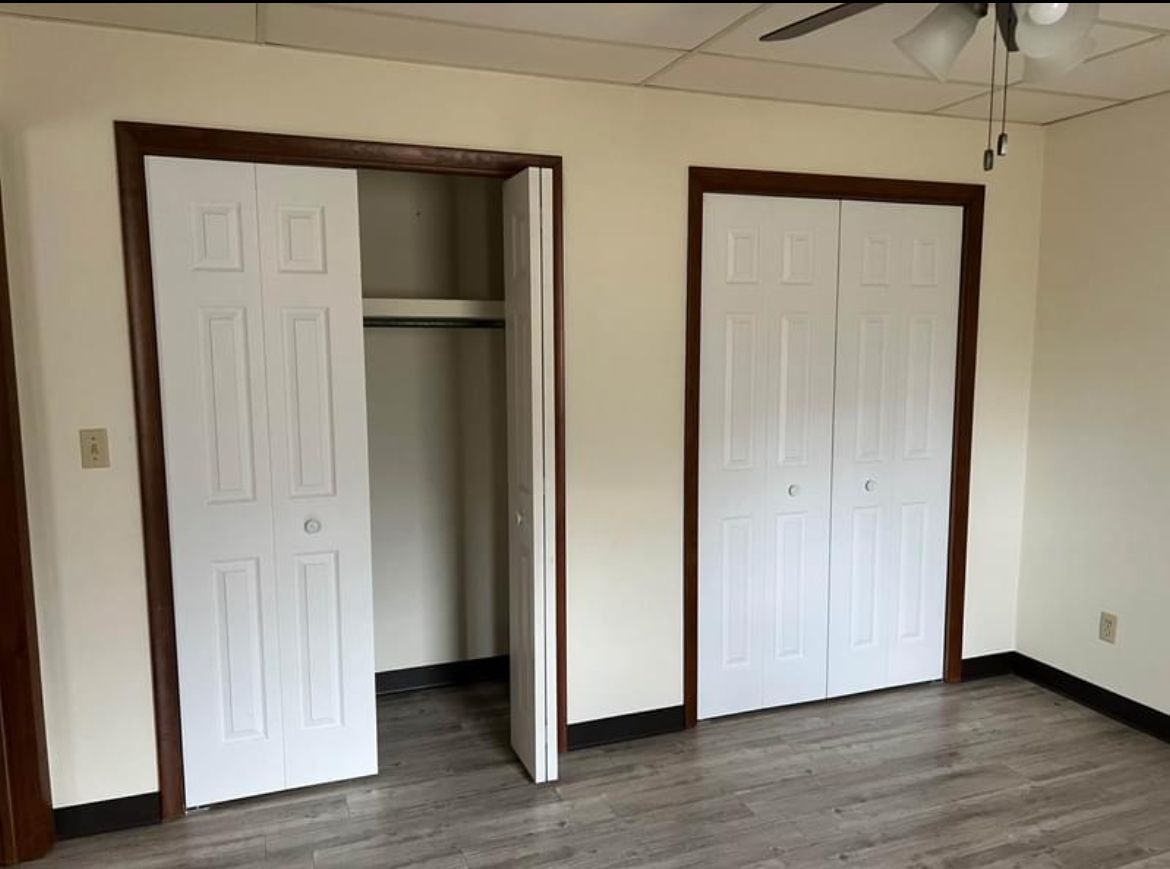 A bedroom with two closets and a ceiling fan.